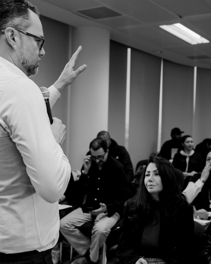 Leandro Marcondes conduzindo um treinamento presencial, com participantes acompanhando.